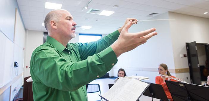 Professor Donald Running conducting flute players in a classroom